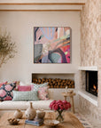 A modern living room with a white sectional sofa, colorful throw pillows, a rustic wooden coffee table, a stone fireplace, and a vibrant abstract painting hanging on the wall.