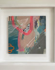 Framed abstract artwork with colorful elements on a light background